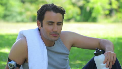 Man Relaxing in Nature with a Water Bottle and Towel