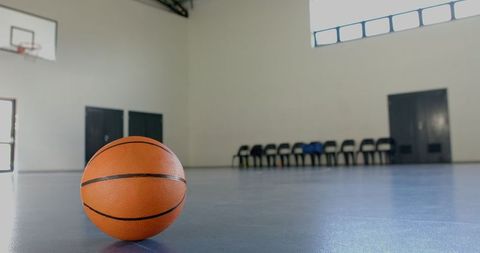 Basketball on Indoor Court with Empty Chairs Background
