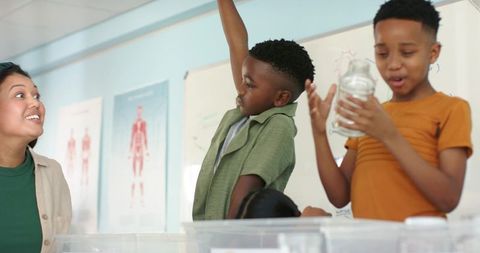 Teacher leading hands-on science experiment with students using clear jars in classroom