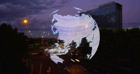 Holographic globe projecting asia over urban night road with neon streetlights and traffic