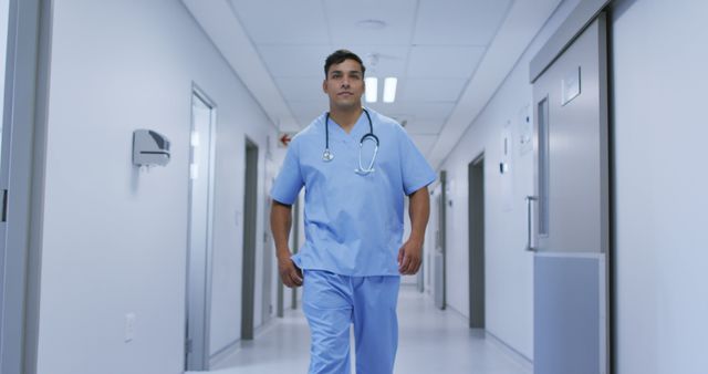 Healthcare professional walking confidently in hospital corridor, wearing scrubs and stethoscope. Ideal for medical industry marketing, hospital promotional materials, healthcare website content, and medical training resources.
