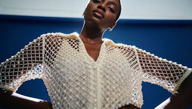 Confident female model posing low-angle in beaded crochet pearl top