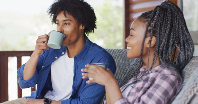 Happy african american couple drinking coffee in log cabin, slow motion. Lifestyle, domestic life, countryside and nature concept.