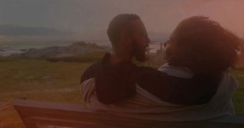 Couple Embracing on Bench by Ocean at Sunset