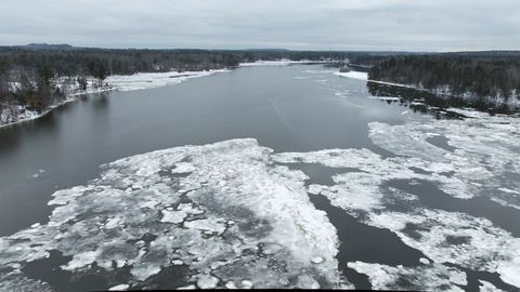 River breaking ice sheets amid snowy forest shoreline under overcast winter sky