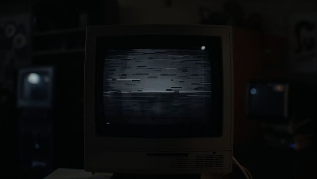 Vintage CRT Monitor Displaying Glitchy Screen in Dimly Lit Workshop