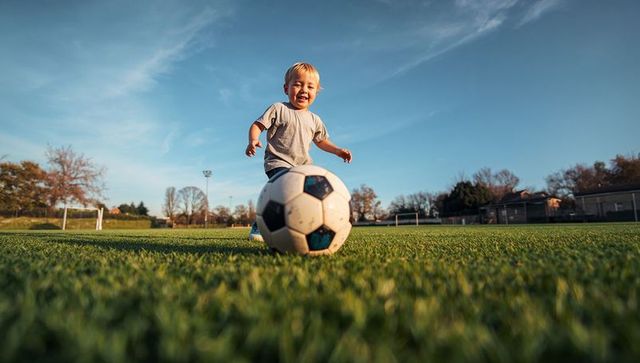 Joyful toddler chasing soccer ball in sunny park