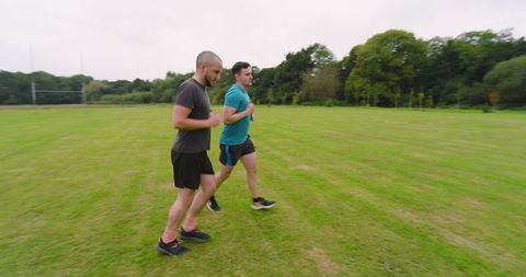 Two men jogging on grassy field in outdoor exercise