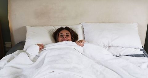 Smiling Woman Relaxing in Bed with Cozy White Duvet