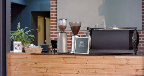 Minimal industrial coffee counter with dual grinders, espresso machine and letterboard