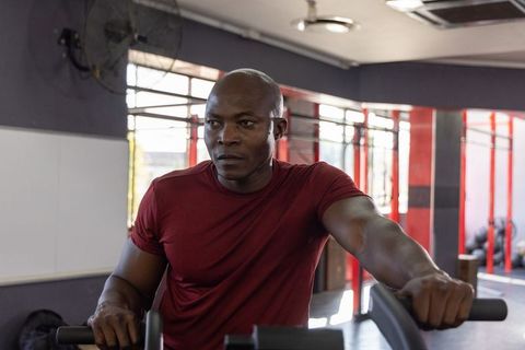 Mature african american man gripping cardio machine focusing during intense gym workout