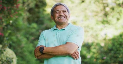 Smiling elderly hispanic man relaxing in sunny garden