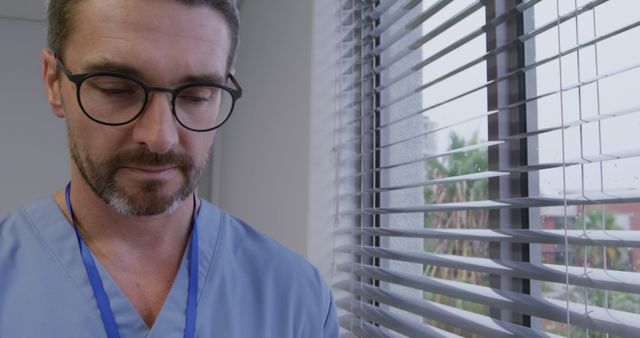 Tired Male Doctor in Scrubs Standing Near Window with Blinds - Download Free Stock Images Pikwizard.com