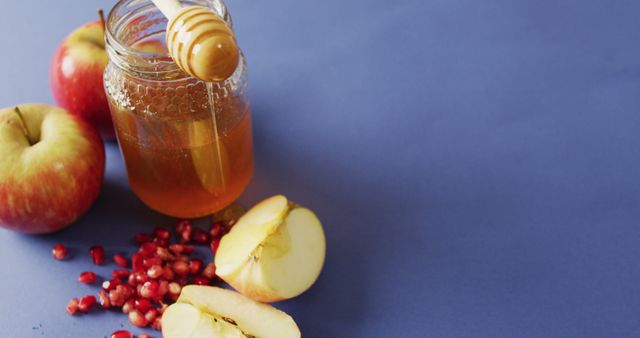 Image of honey in jar, cranberries, apples and apple slices lying on blue surface. food, cooking, baking, taste and flavour concept.