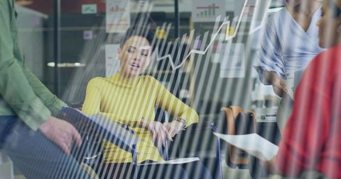 Businesswoman checking watch during team meeting with glass charts and growth graph