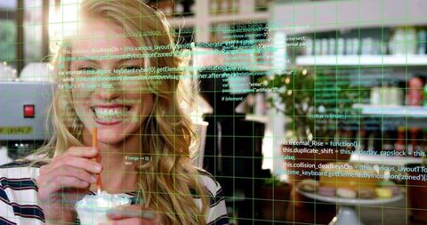 Smiling woman holding iced whipped-cream drink at cafe wearing striped top with green code overlay