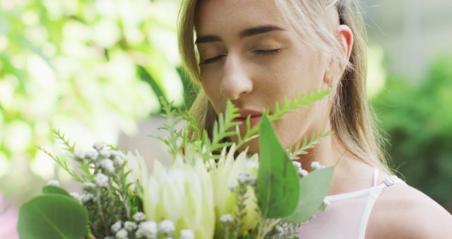 Woman is enjoying the scent of fresh flowers outdoors. Ideal for concepts related to relaxation, nature, peaceful moments, floral beauty, gardening, and mental wellness.