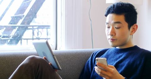 Focused man multitasking with smartphone and tablet