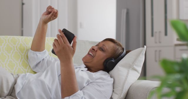 Mature Woman Relaxing on Couch with Headphones and Smartphone - Download Free Stock Images Pikwizard.com