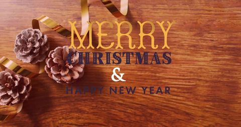Merry christmas & happy new year typography on warm wood with frosted pine cones