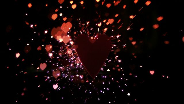 Heart-shaped object surrounded by sparks and confetti flying in dark background, ideal for festive and romantic themes. Perfect for creating advertisements, greeting cards, or social media posts celebrating love, relationships, and festive occasions.