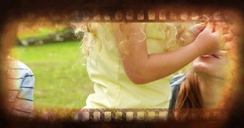 Child offering red fruit to smiling woman in park during family picnic bonding moment