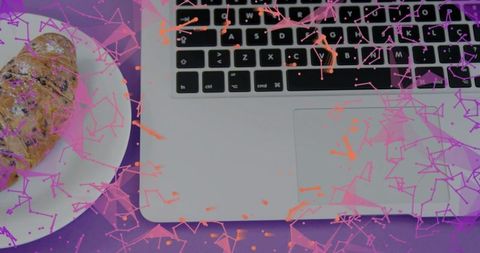 Remote work laptop with croissant featuring pink-orange geometric confetti overlay