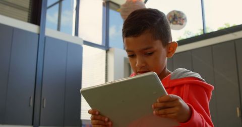 Young boy engaged with tablet in modern classroom environment