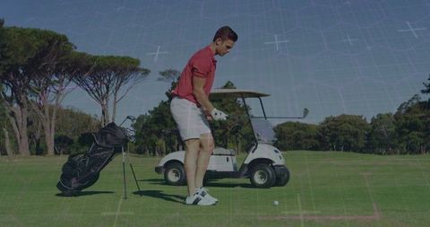 Male Golfer Preparing Swing on Lush Golf Course with Cart