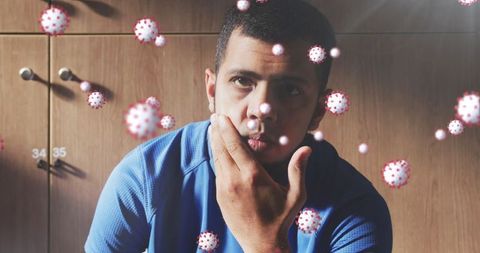 Athlete contemplating in locker room with floating viruses