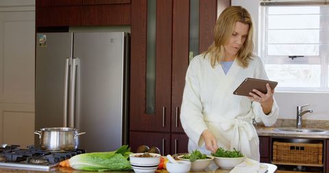 Woman following recipe on digital tablet in modern kitchen