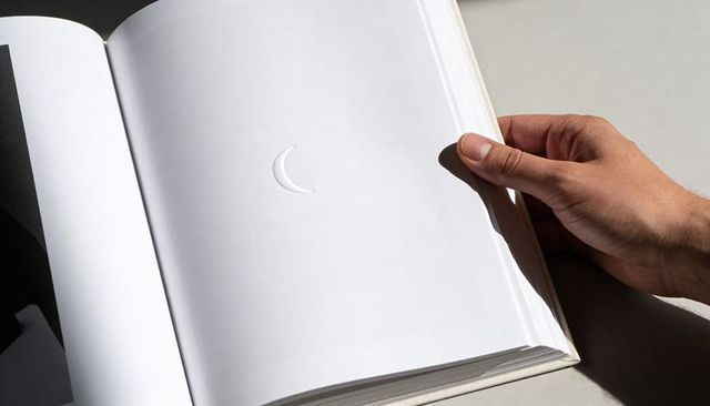Gripping Hand Turning Blank Page with Embossed Crescent Minimal Monochrome Closeup
