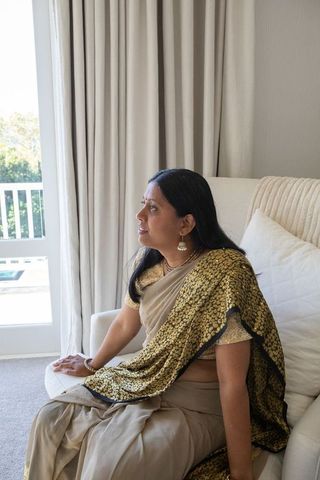 Elegant indian woman in saree sitting calmly by window