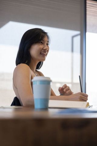 Asian woman writing in study room with coffee for productivity