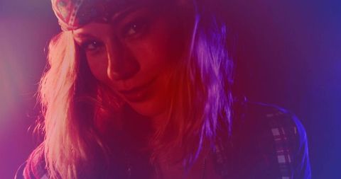 Posing mid-adult woman wearing bandana and plaid shirt under neon rimlight moody portrait