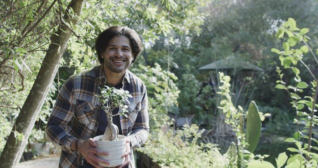 Man Smiling While Holding Houseplant in Garden - Download Free Stock Images Pikwizard.com