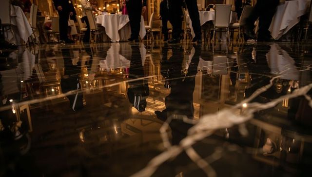 Glossy marble floor reflecting formal attire and chandeliers at upscale gala reception