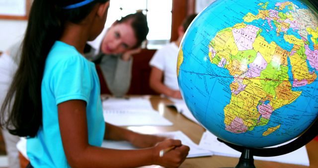 Pupils all siting around table working with focus on globe in elementary school