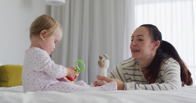 Caucasian mother and baby playing with toys on the bed at home. motherhood, love and childcare concept