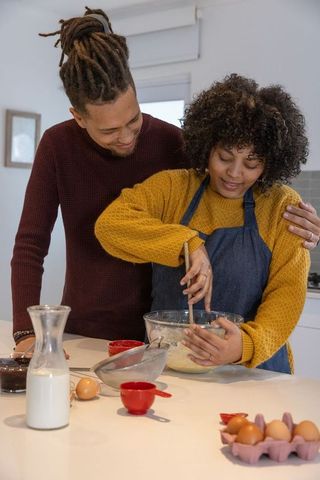 African american couple mixing batter in sunlit kitchen sharing cozy home baking moment
