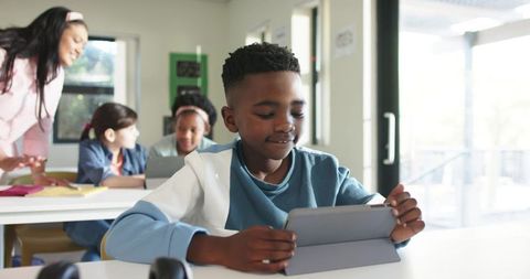 African American Boy Using Tablet in Bright Classroom for Collaborative Digital Learning