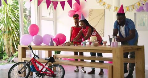 Family decorating birthday party with balloons and cake