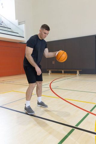 Male basketball player dribbling on indoor gym court practicing ball control and footwork