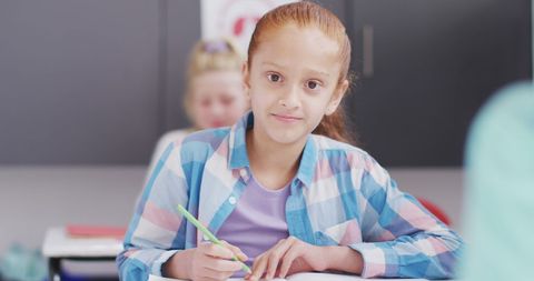Smiling Schoolgirl Writing in Classroom Engaged in Learning Activity - Download Free Stock Images Pikwizard.com