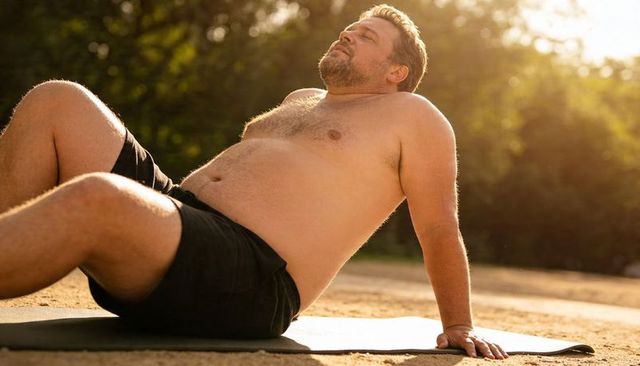 Middle-aged man relaxing on exercise mat outdoors at golden hour for fitness recovery