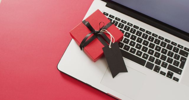 Laptop and red gift box with black ribbon and gift tag, on red background with copy space - Download Free Stock Photos Pikwizard.com