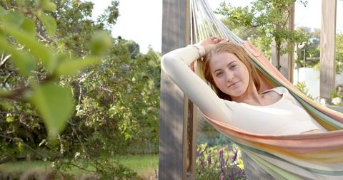 Young woman relaxing on multicolored hammock in peaceful garden setting