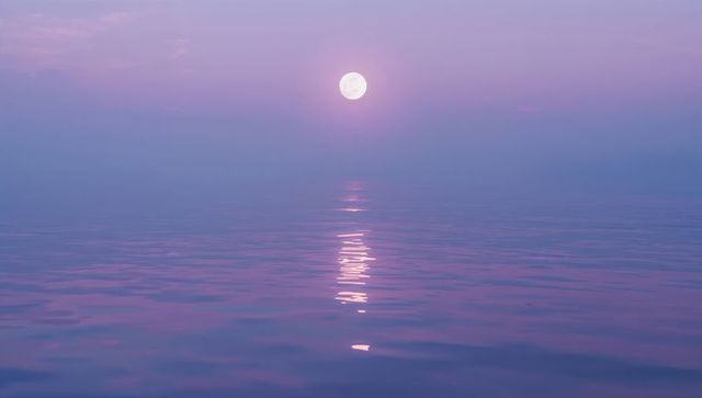 Full moon reflecting across serene ocean at twilight