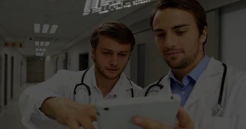 Doctors Consulting on Tablet for Diagnosis in Hospital Corridor