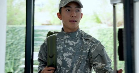 Asian soldier in camouflage at home entryway